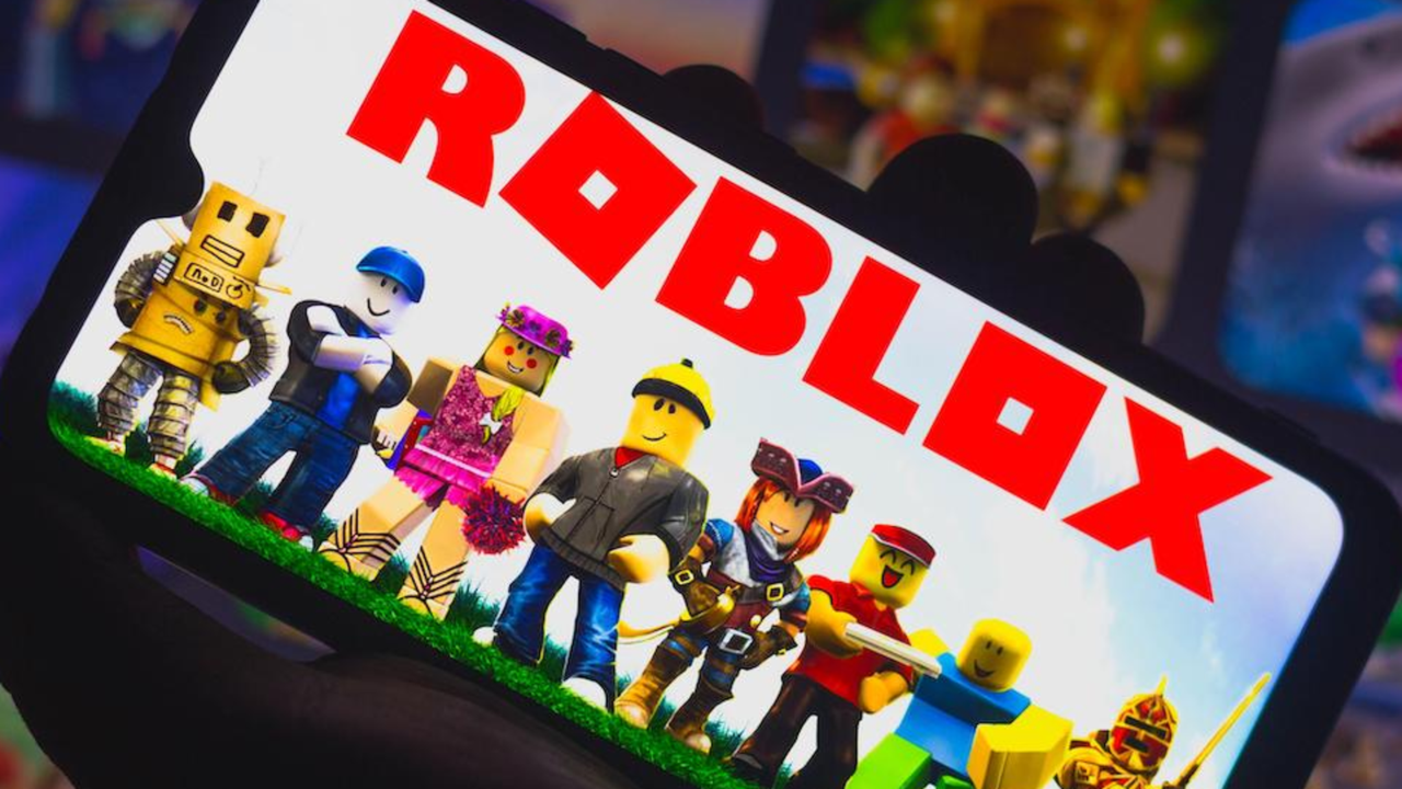 Roblox 徽标和显示在某人手中的移动设备屏幕上的各种游戏角色